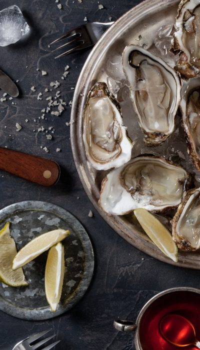 Open oysters on a plate with slices of lemon and ice